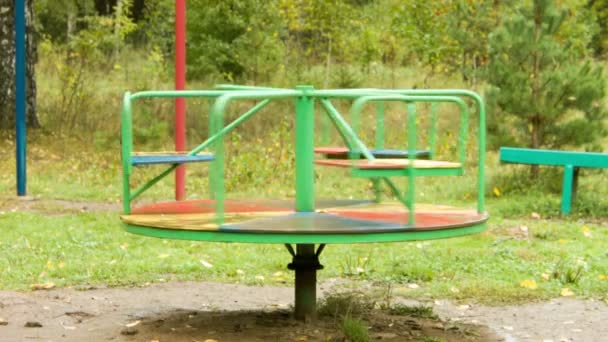 Rotatie van een carrousel in de regen op de lege speelplaats - Video