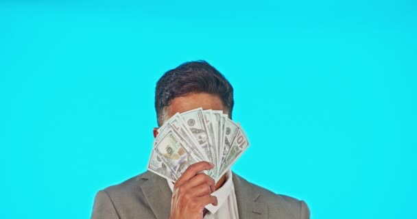 Business man, money fan and winner in studio isolated on a blue background mockup. Cash, winning and rich Indian person smell, thinking or sniffing dollars after lottery, bonus prize or competition - Footage, Video