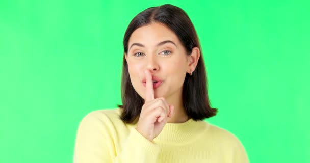 Wink, secret and face of a woman on a green screen isolated on a studio background. Quiet, silent and portrait of a winking girl with finger on mouth for silence, privacy and gossip on a backdrop. - Footage, Video
