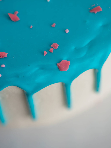 studio shot of chocolate frosted blue dripped icing white cup cake, unicornio, merengue y salpicaduras en la parte superior - Foto, Imagen