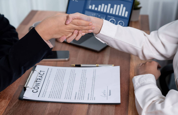 Two professionals successfully close business deal with closeup handshake, sealing the partnership agreement. Legal document and signature as formal agreement between the two companies. Enthusiastic - Foto, imagen