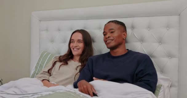 Relax, watching tv and cuddle with interracial couple in bedroom for streaming, affectionate and movie. Happy, bonding and weekend with black man and woman at home for television, film and free time. - Footage, Video