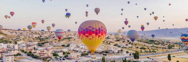 BANNER, LONG FORMAT Colorful hot air balloons flying over at fairy chimneys valley in Nevsehir, Goreme, Cappadocia Turkey. Spectacular panoramic drone view of the underground city and ballooning - Fotoğraf, Görsel