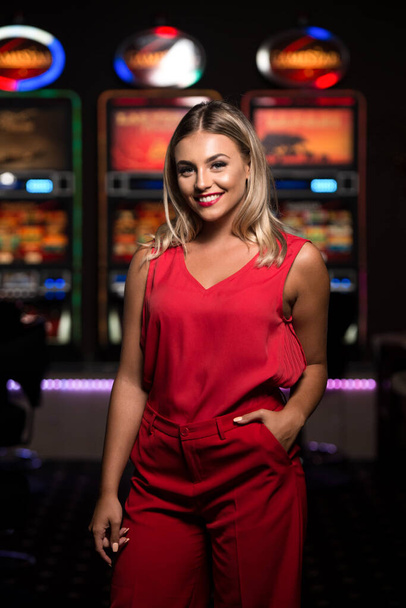 Portrait of a Young Beautiful and Well Dressed Caucasian Girl in Red Dress Playing in the Casino and Celebrate - 写真・画像