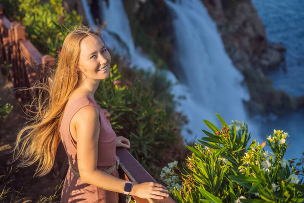 Beautiful woman with long hair on the background of Duden waterfall in Antalya. Famous places of Turkey. Lower Duden Falls drop off a rocky cliff falling from about 40 m into the Mediterranean Sea in - Zdjęcie, obraz