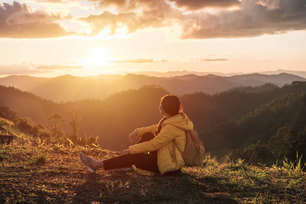 Happy young woman traveler relaxing and looking at the beautiful sunrise on the top of mountains, Travel lifestyle concept - Foto, afbeelding