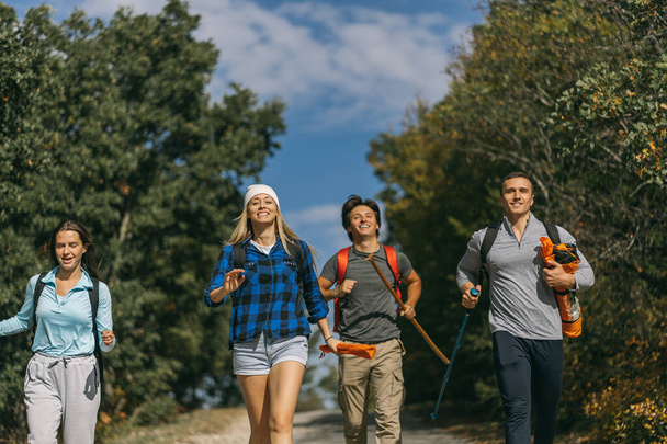 Blonde girl, hiker, running with her friends on the street after hiking all day - Photo, Image