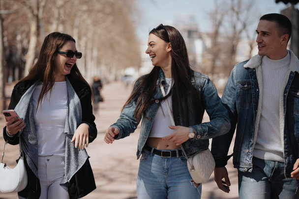 Primo piano di tre migliori amici che ridono e si divertono mentre camminano in città - Foto, immagini