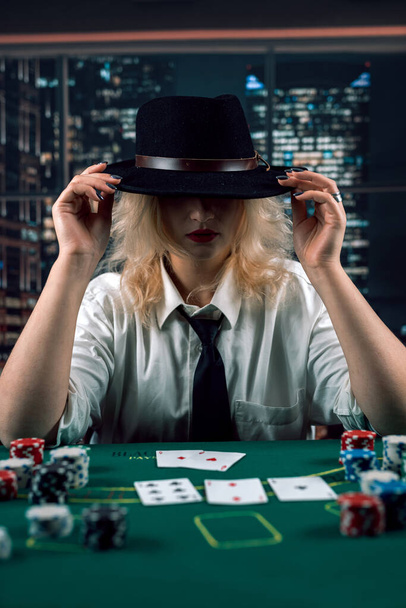 chica atractiva en camisa y sombrero jugando al póquer y sosteniendo cartas en el casino. Jugadora de mujeres. excitación - Foto, imagen