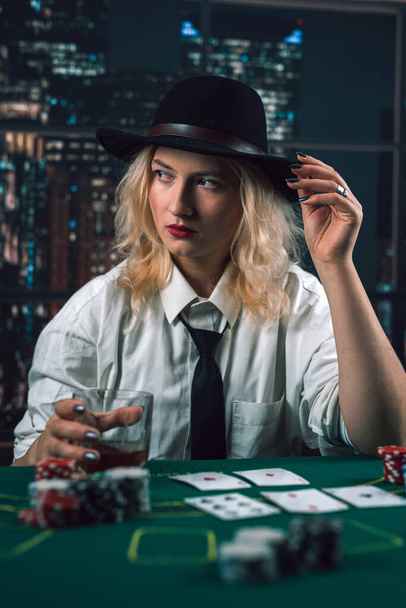 dealer een mooi meisje in een streng shirt met een stropdas deelt kaarten. Casino gokken voor geld. de dealer is een vrouw - Foto, afbeelding