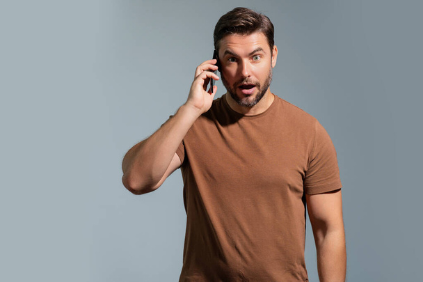 Satisfied business man talking on phone, promo mobile app. Businessman in casual clothes using smartphone isolated on studio background. Portrait of cheerful guy using cellphone, browse social media - Photo, image