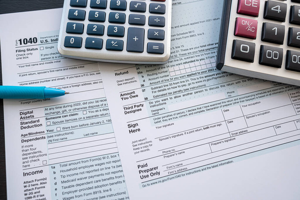 Steuerformular 1040 mit Stift und Taschenrechner auf dem Schreibtisch. Jahresbericht, dedline. Zeit für Steuern - Foto, Bild