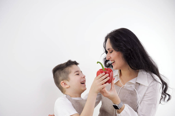 Mulher feliz picando pimentão vermelho enquanto está com as crianças na cozinha. Foto de alta qualidade - Foto, Imagem