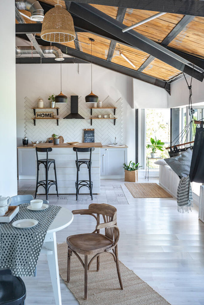 stylish kitchen interior design. white walls and wooden decoration. beautiful hammock and high windows. - Фото, изображение