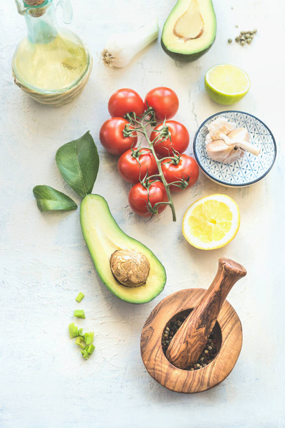 Fresh ingredients : avocado, tomatoes, lemon , garlic and olives oil for tasty salad making, top view. Healthy food.  Vegetarian lunch or snack - Foto, Bild