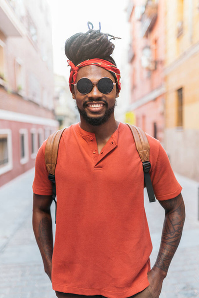 Stock photo of happy african american boy with dreadlocks and a bandana walking in the street. - Photo, Image