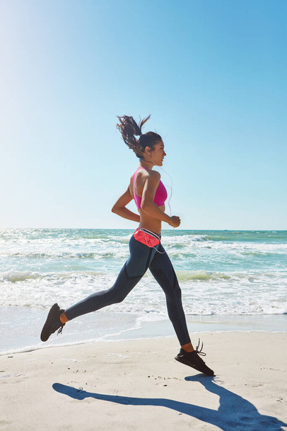 Get running, get fit. an attractive young woman working out on the beach - Photo, Image