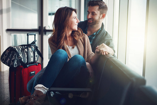 Sen benim her şeyimsin. Havaalanında bavullarıyla oturan ve birbirlerine bakıp duran genç bir çift. - Fotoğraf, Görsel