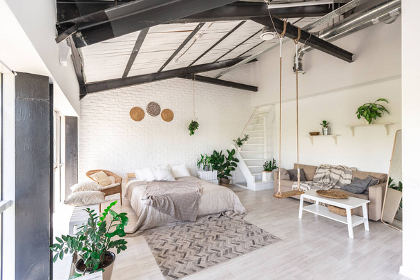 Luxury bedroom design in a rustic cottage in a minimalist style. white walls, panoramic windows, wooden elements of decoration on the ceiling, rope swings in the middle of a spacious room. - Фото, изображение