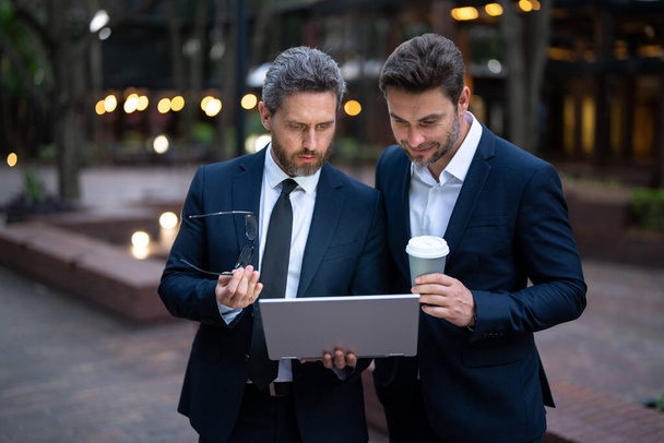Business men with takeaway coffee and laptop outdoor were strategic in their planning. Business men were effective communicators. Business men team using laptop outdoor. Businessmen looking laptop - Фото, изображение