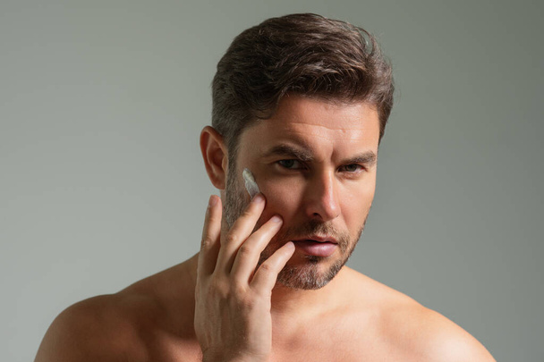 Man care of skin. Charming man with perfect soft skin. Male beauty and skincare concept. Man cosmetic, skin treatment. Morning hygiene. Mens cosmetics and wellness. Skincare. Man with cream on face - Photo, image