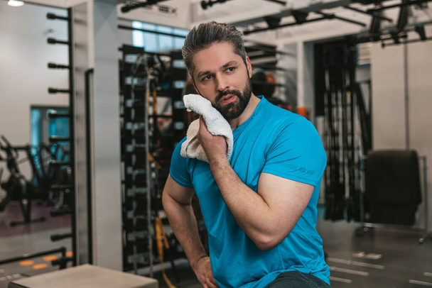 Exhausted. Young man wiping sweat with the towel after workout - Fotó, kép