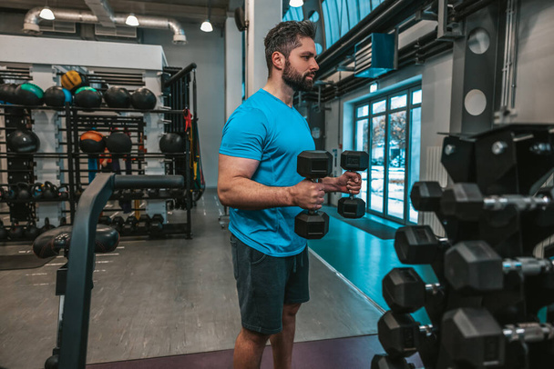 Athlete. Man working with dumbbells in a sports club - Photo, image