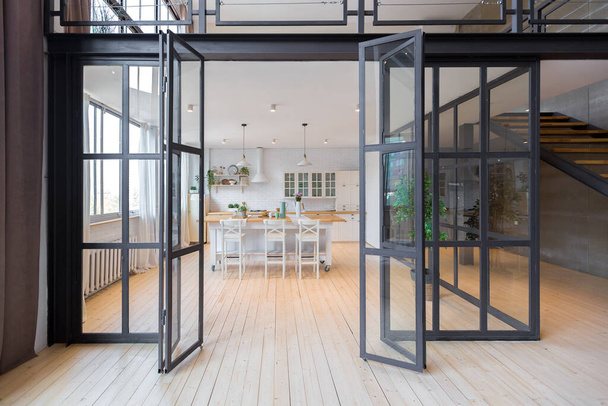 trendy modern design two-level apartment with large high windows. The stylish living room and kitchen in bright colors are undressed by a glass partition. bedroom on the second floor. - 写真・画像