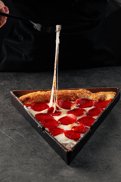 Juuston vetäminen pepperonipizzasta haarukalla - Valokuva, kuva