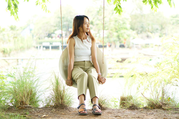 Happy Asian woman on a swing in the park - Foto, imagen