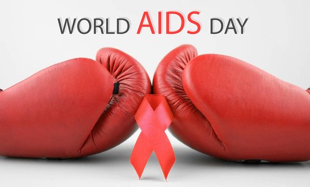 Red ribbon with boxing gloves, wrestling symbol. World AIDS Day and National HIV, AIDS and Aging Awareness Month. - Foto, immagini