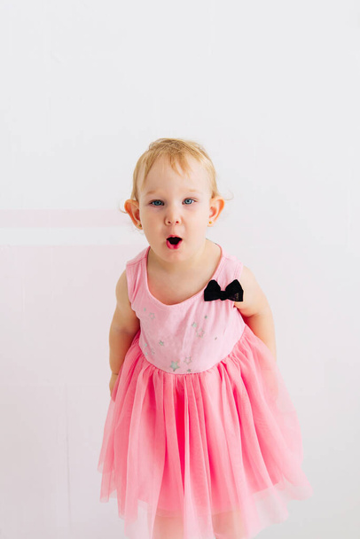 concept of children's emotions. Portrait of lovely toddler little baby child with pink dress - Photo, Image