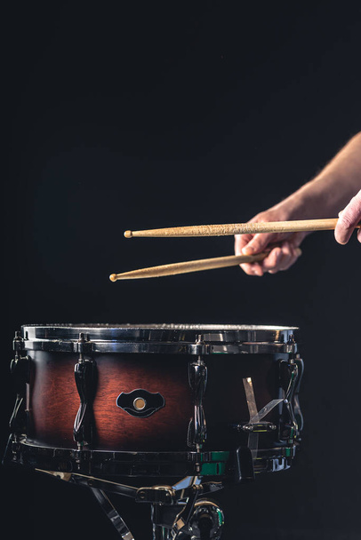 Een mannelijke drummer speelt de snare drum op een donkere achtergrond, een muzikale percussie instrumentman. - Foto, afbeelding