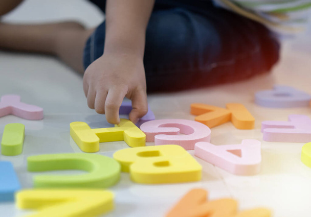 選択的フォーカス。幼児の男の子は自宅で床の上にアルファベットの文字を学ぶ。知的ゲーム就学前初等教育の概念. - 写真・画像