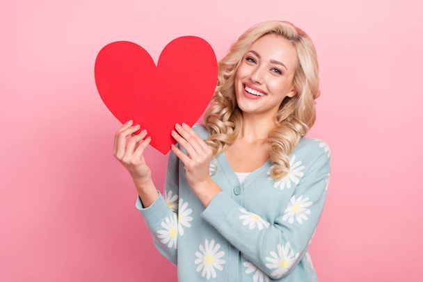 Portrait of cheerful pretty person toothy smile arms hold paper heart shape card isolated on pink color background. - Фото, изображение