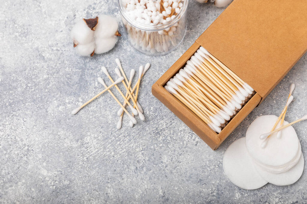 Cotton swabs in craft packaging and holder on a gray cement background. Bamboo cotton buds. Means for hygiene of ears. Eco-friendly materials.Hygienic cotton ear buds. - Photo, Image