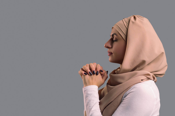 Modlitwa. Młoda kobieta w hidżabie modli się z zamkniętymi oczami - Zdjęcie, obraz