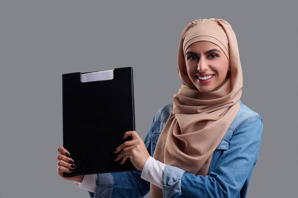 Ευτυχισμένη γυναίκα. Αραβική νεαρή γυναίκα σε μπεζ χιτζάμπ φαίνεται ευτυχισμένη και ικανοποιημένη - Φωτογραφία, εικόνα
