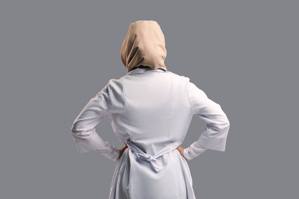 Woman in lab coat. Woman in hijab and lab coat staning backside - Photo, Image