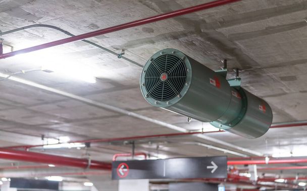 Jet fan at underground parking area. Ventilation fan in the parking lot. Air flow system. Ventilation system in underground car parking lot at commercial building. Duct fan air ventilation at mall. - Foto, afbeelding