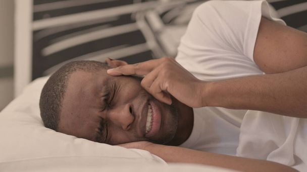 ベッドに横たわっ頭痛を持つアフリカの男の側面図 - 写真・画像