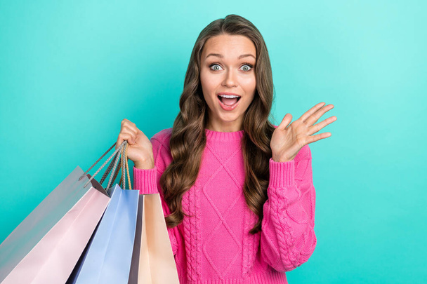 Photo of excited funky girl wear pink sweater rising arm holding shoppers open mouth isolated turquoise color background. - Photo, image