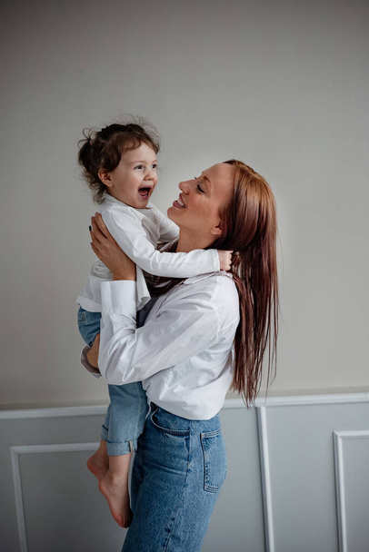 Happy young adult mom holding her adorable laughing child girl . Mother and daughter having fun together - Valokuva, kuva