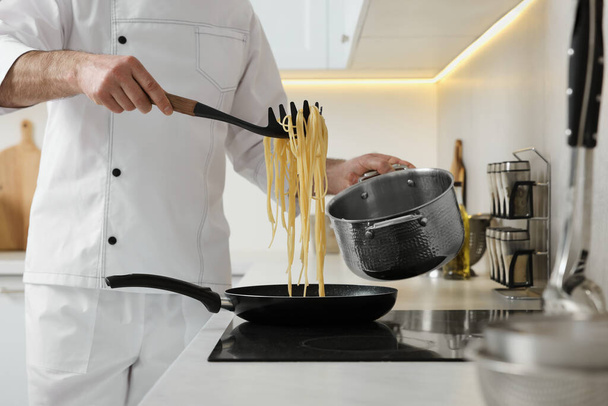 Professional chef cooking delicious pasta on stove in kitchen, closeup - Fotoğraf, Görsel
