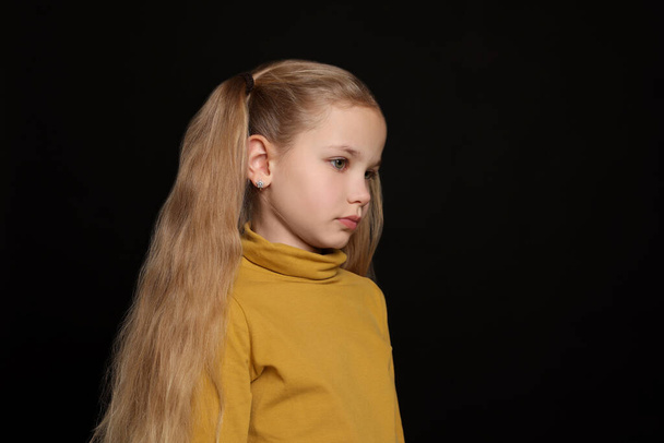 Little girl on black background, space for text. Children's bullying - Zdjęcie, obraz