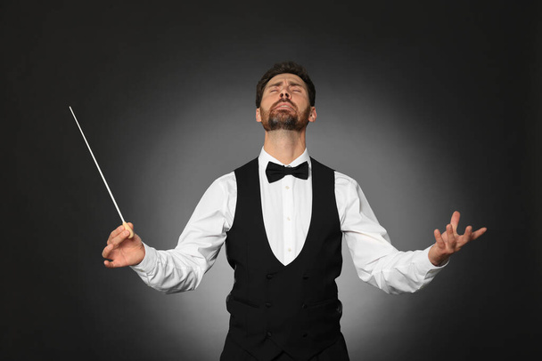 Professional conductor with baton on black background - 写真・画像