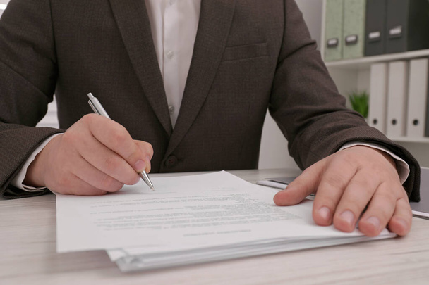 Man signing document at wooden table, closeup - Fotó, kép