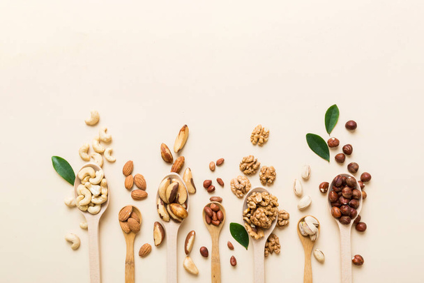 mixed nuts in white wooden spoon. Mix of various nuts on colored background. pistachios, cashews, walnuts, hazelnuts, peanuts and brazil nuts. - Photo, Image