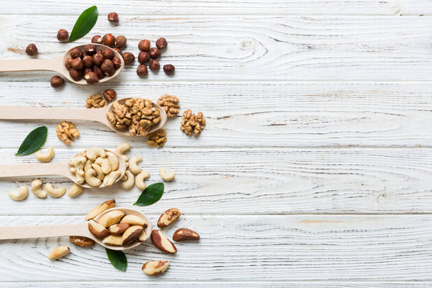mixed nuts in white wooden spoon. Mix of various nuts on colored background. pistachios, cashews, walnuts, hazelnuts, peanuts and brazil nuts. - Foto, immagini
