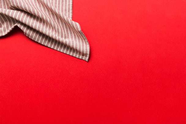 bovenaanzicht met rood leeg keukenservet geïsoleerd op tafelachtergrond. Opgevouwen doek voor mockup met kopieerruimte, Vlakke lay. Minimale stijl. - Foto, afbeelding